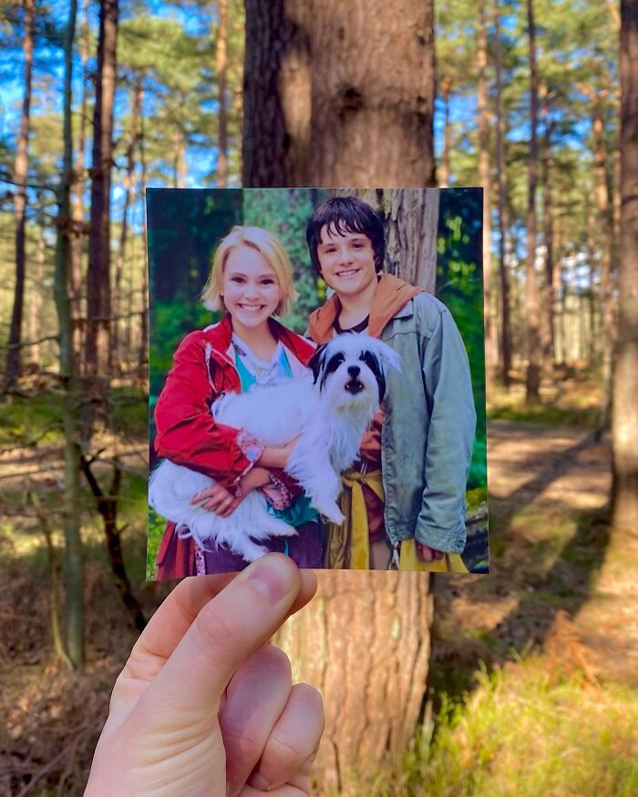 Hand holding photo of two kids with a dog in a forest, comparing real-life filming locations of movie and TV show scenes.