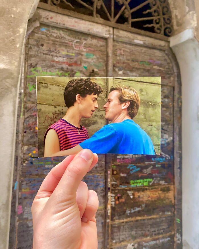 Hand holding a photo from a movie scene aligned with the real-life filming location of a graffiti-covered door.