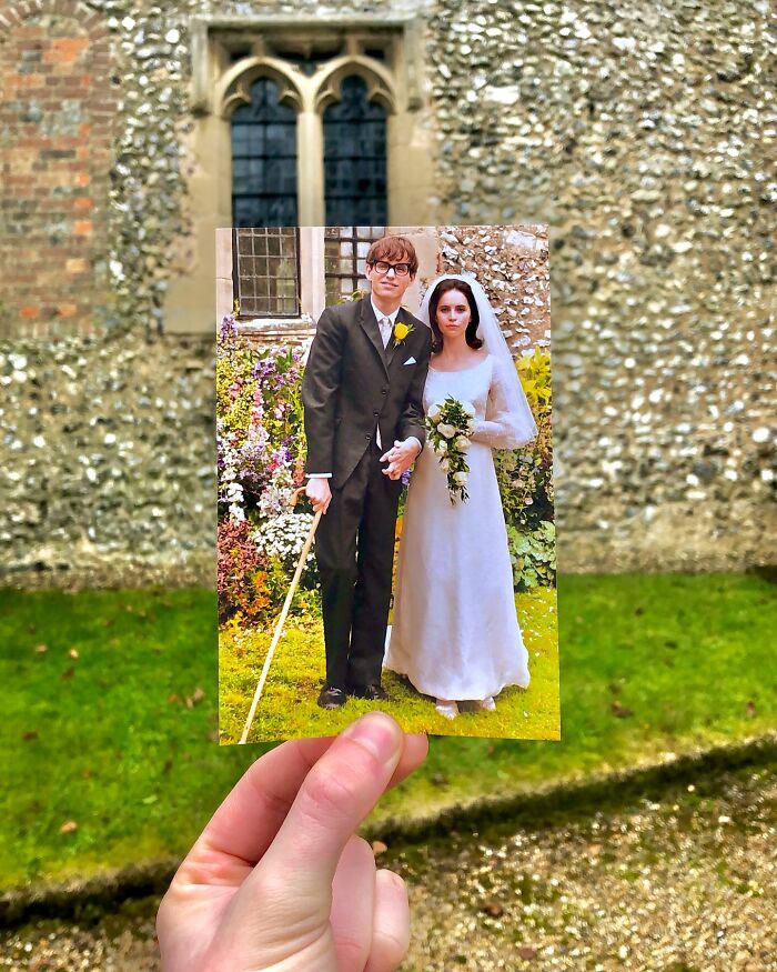 Hand holding photo of wedding scene at real-life filming location compared by photographer outdoors on grass.