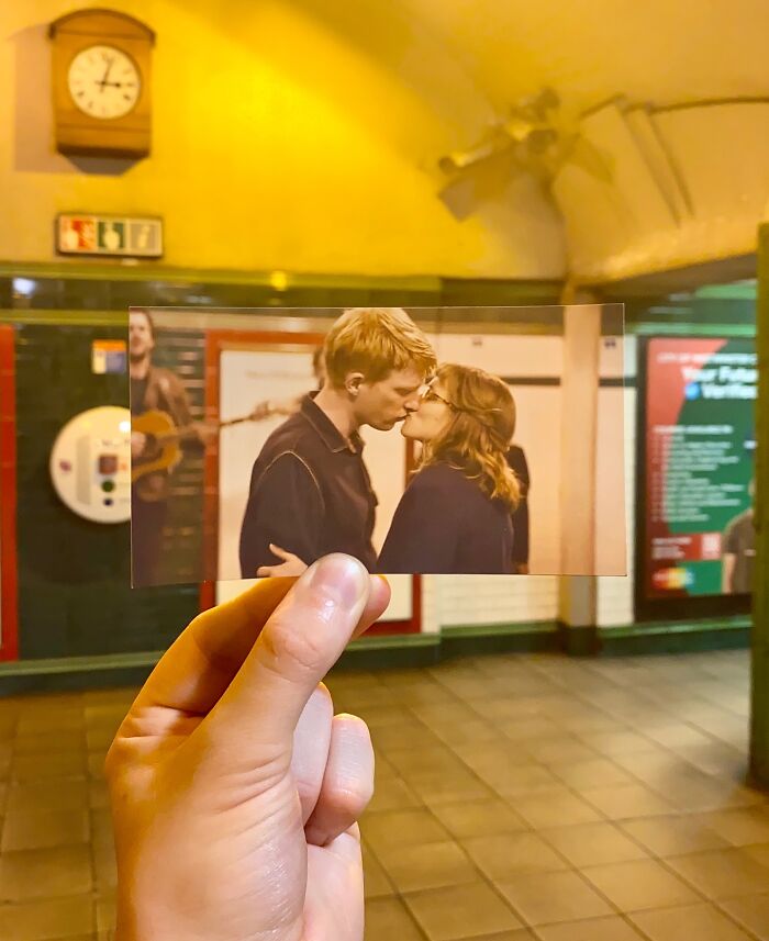 Hand holding photo of a kissing couple aligned with the real-life filming location in a subway station scene.