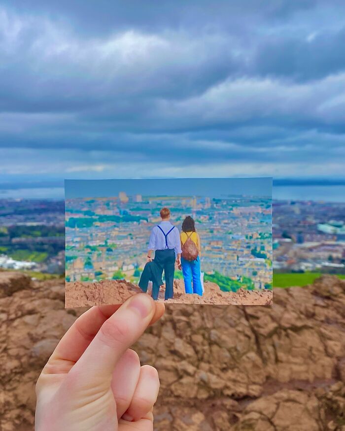 Hand holding photo comparing real-life filming location of movie and TV show scene with cityscape background.
