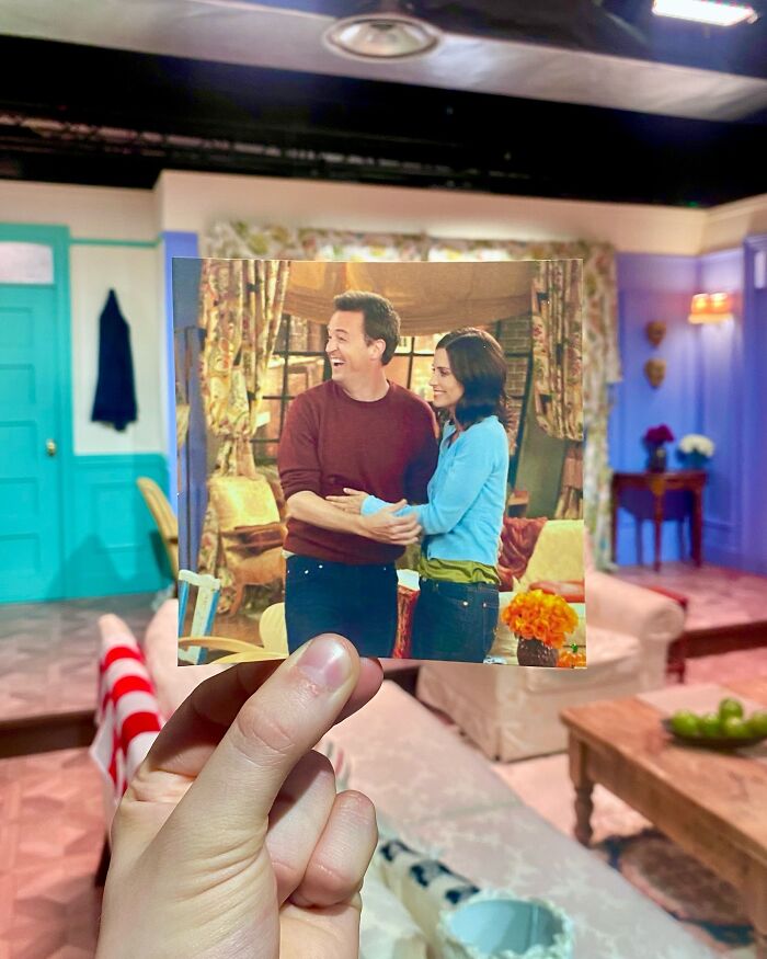 Hand holding photo of TV show scene inside the original real-life filming location of the Friends apartment set.