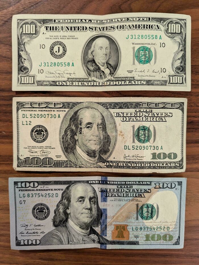 Three 100 dollar bills from different years showing how things used to look in US currency design changes.