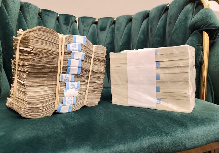 Stacks of worn and crisp folded bills displayed on a green velvet chair showing money before and after changes