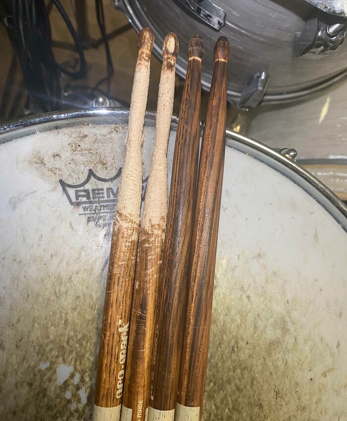 Two pairs of wooden drumsticks showing before and after photos of wear and tear on a drumhead surface.