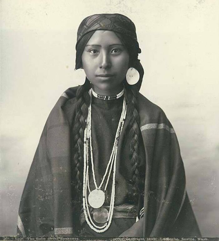 Native American female with braided hair and traditional jewelry in a time-weathered photograph honoring strength.
