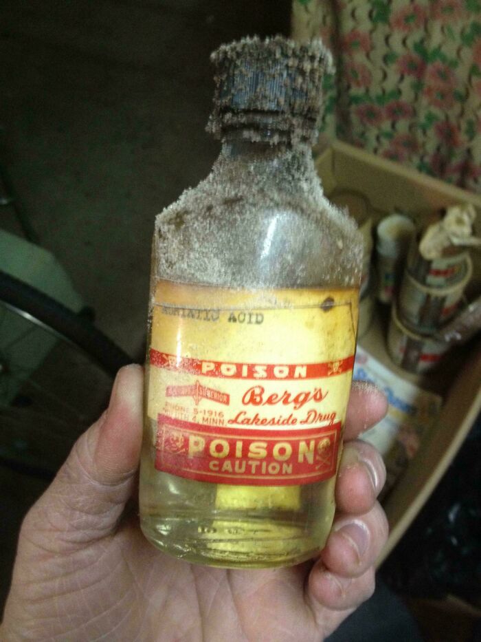 Hand holding an old poison bottle with a faded label, one of the bizarre things found in old houses.