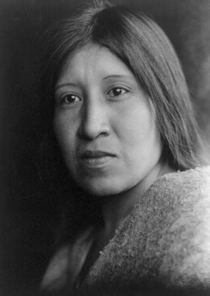 Native American woman in a time-weathered black and white photograph portraying female strength and resilience.