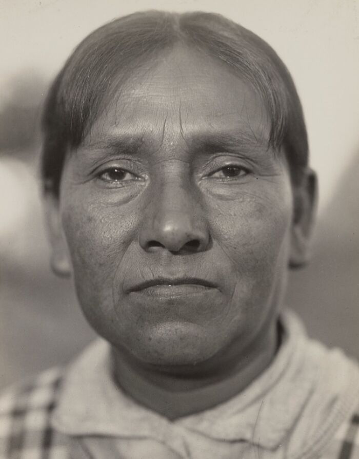 Close-up portrait of a Native American woman showcasing time-weathered strength and resilience in black and white.