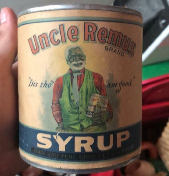 Hand holding vintage Uncle Remus syrup can, a bizarre thing found in old houses, with faded label and worn colors.