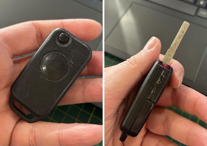 Hand holding a worn black car key on a green textured surface and near a laptop keyboard, found in old houses.
