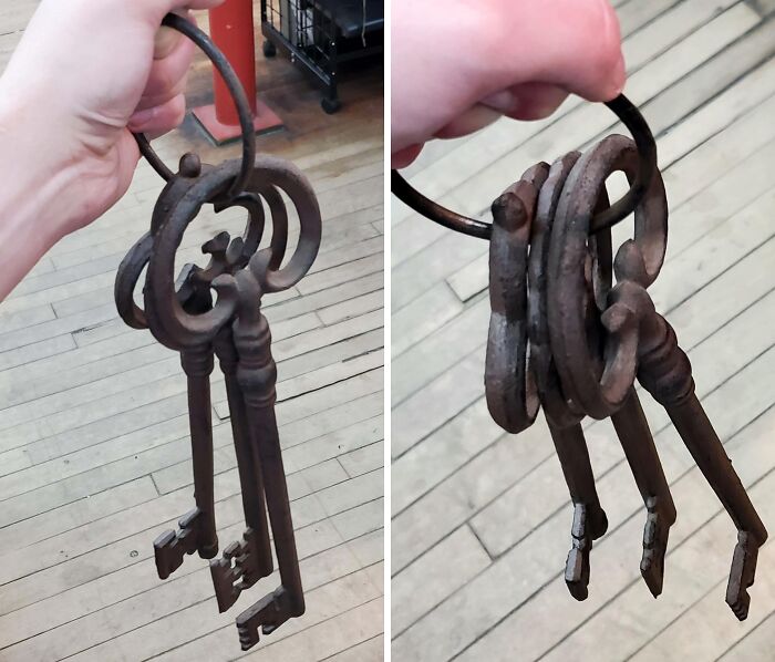Rusty old metal keys with circular tops and ornate designs, found in an old house, held on a metal ring.
