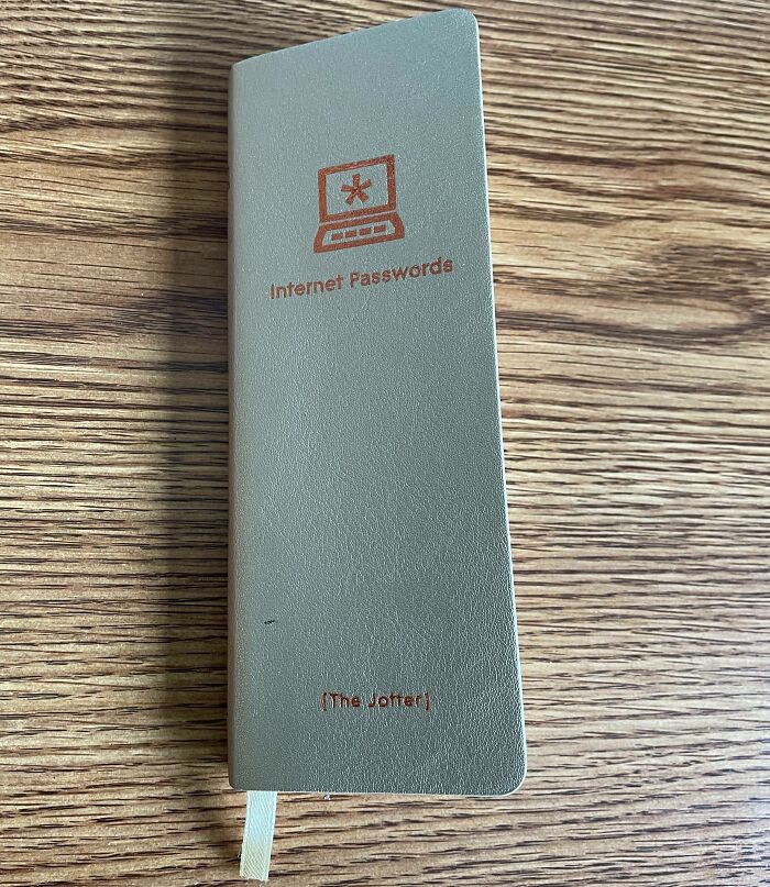 Notebook labeled internet passwords found among bizarre things in old houses, placed on a wooden surface.