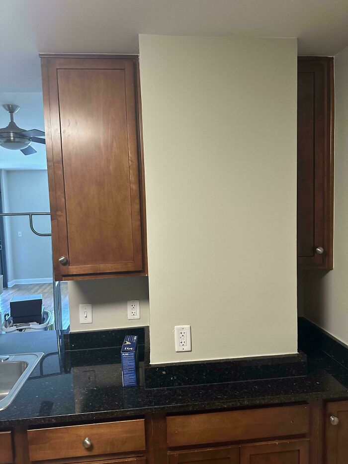 Kitchen interior design mistake with wall blocking counter space and electrical outlets behind cabinets and countertop.