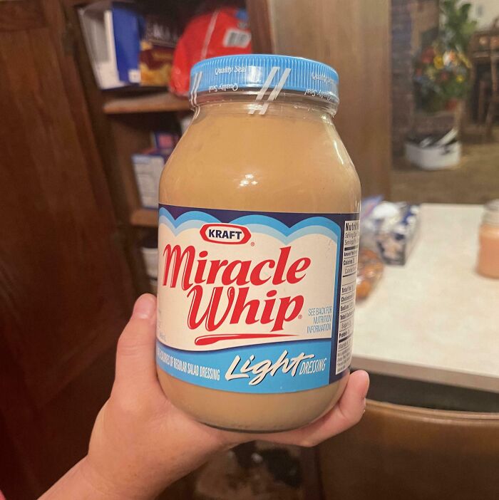 Hand holding a jar of Kraft Miracle Whip Light dressing, a bizarre item found in an old house kitchen.