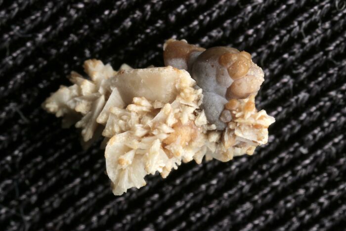 Cálculo renal en primer plano mostrando detalle interesante y curioso del cuerpo humano sobre fondo oscuro tejido textil.