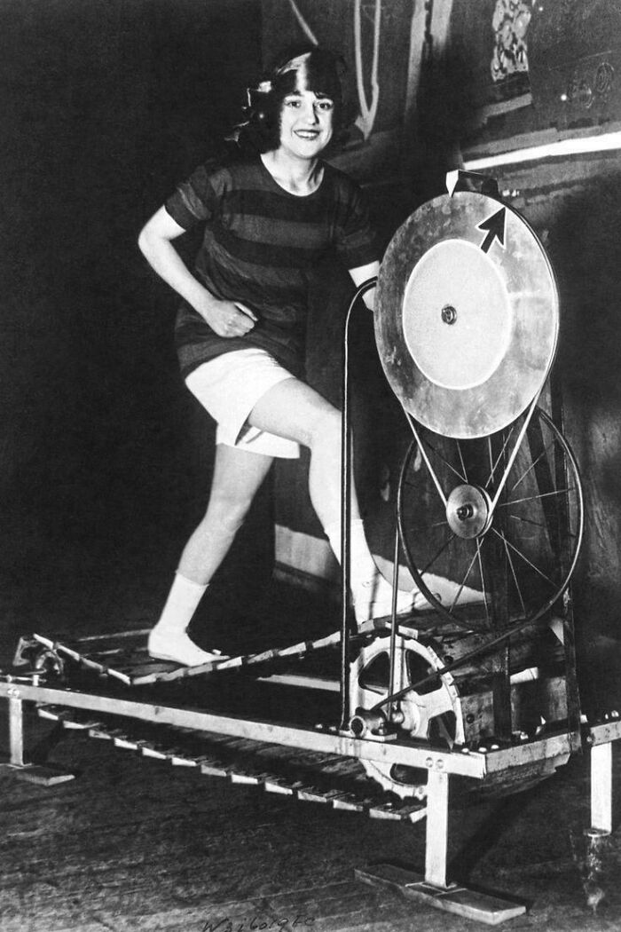 Young woman using an early treadmill exercise machine demonstrating fascinating pictures for curious minds.
