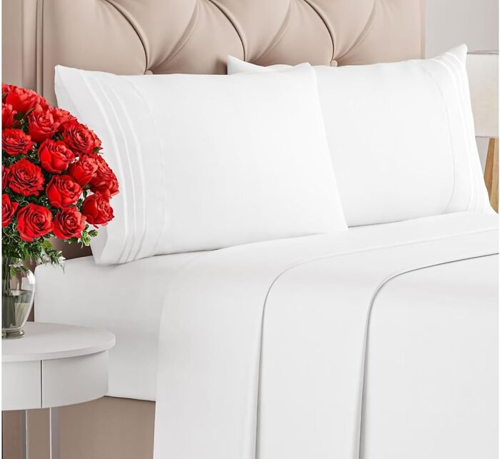 White bed sheets and pillows displayed on a bed with a vase of red roses, Amazon Memorial Day Sale finds.