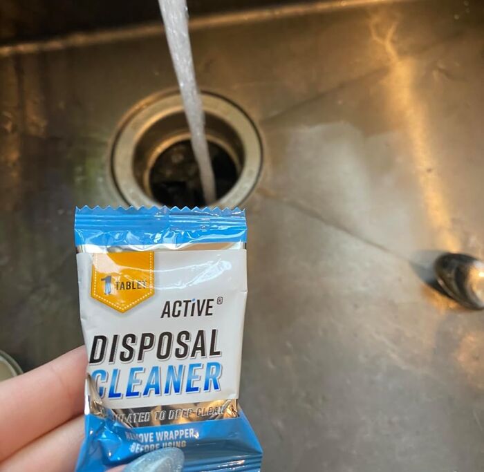 Packet of disposal cleaner held over kitchen sink drain with water running, featured in Amazon Memorial Day sale finds.