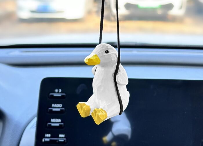 White and yellow duck car ornament hanging in front of a car dashboard during the Amazon Memorial Day sale fade-out.