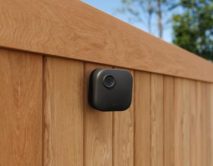 Outdoor security camera mounted on wooden fence, featured in Amazon Memorial Day sale for quick home protection deals.