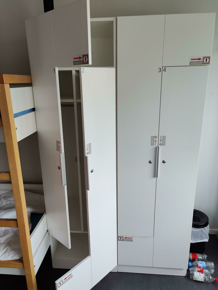 Cabinet doors in a dangerous design with multiple warning stickers, illustrating a potential death trap hazard in storage furniture.