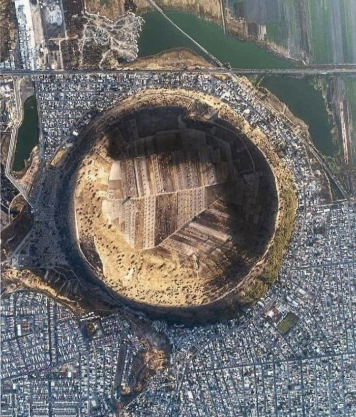 Aerial view of a large circular crater surrounded by an urban area, showcasing an odd discovery on Google Earth.