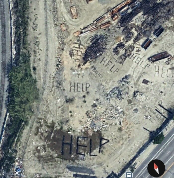Aerial Google Earth view showing the word HELP spelled multiple times on barren land near a street intersection.