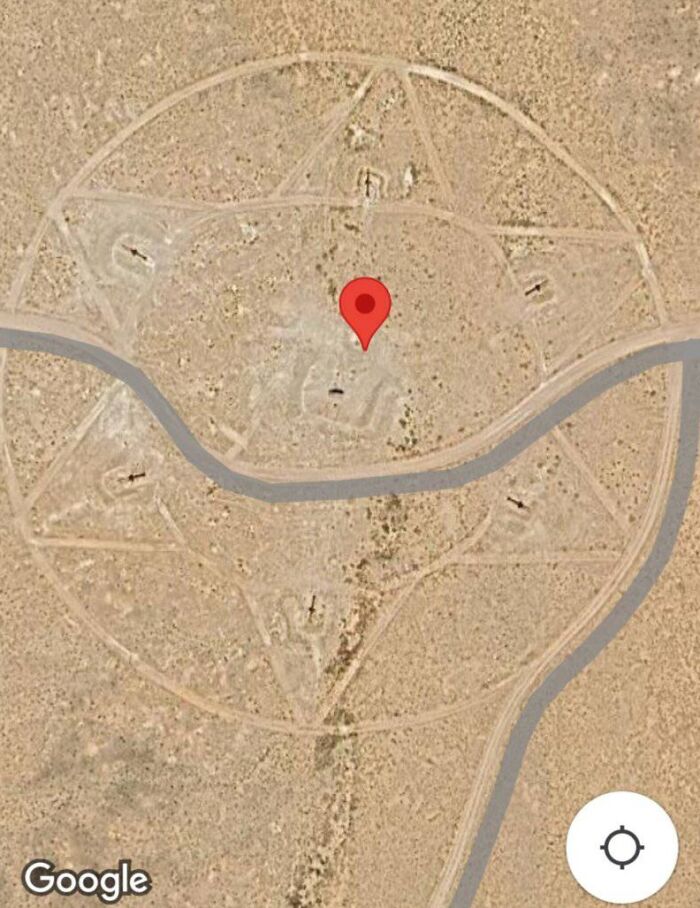 Aerial view of an odd pentagram shape in the desert found on Google Earth with marked coordinates and road nearby.