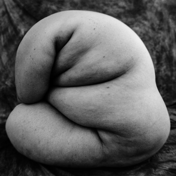 Black and white intimate, cinematic-looking shot of a curled figure captured using vintage photography techniques.