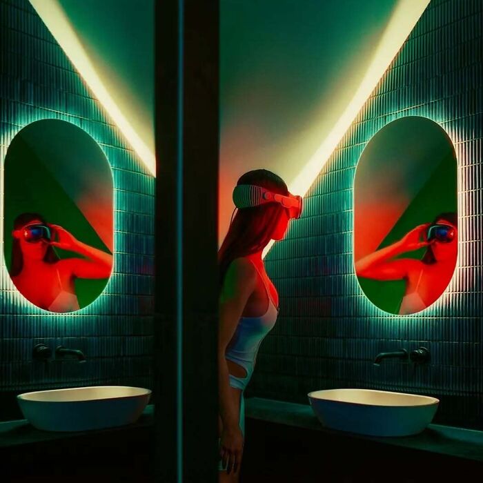 A woman wearing a VR headset stands in a neon-lit bathroom, reflected in two oval mirrors, creating a cinematic vintage vibe.