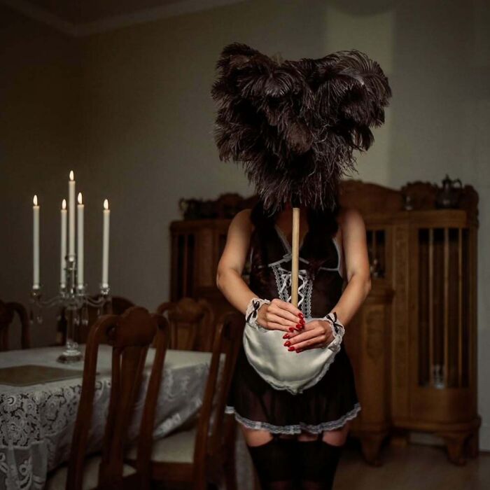 Person holding large feather duster, dressed in vintage style, captured with vintage cameras for cinematic-looking shots.