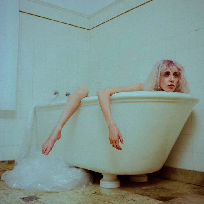 Woman with blonde hair in a bathtub, captured in an intimate, vintage-style cinematic photograph.