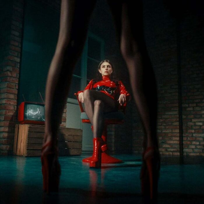 Woman in red boots and outfit sitting on chair in a cinematic vintage style shot captured with vintage cameras.