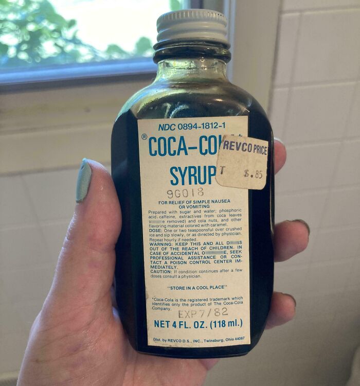 Hand holding a vintage Coca-Cola syrup bottle, an unusual find in old houses that puzzled many collectors.