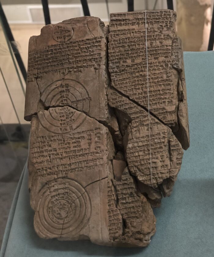 Ancient clay tablet with detailed cuneiform writing and circular diagrams, a bizarre historical artifact display.