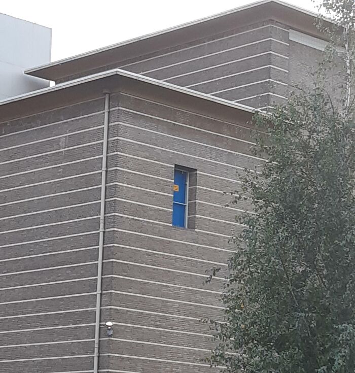 Unusual building design with a high narrow door on an upper floor, showcasing dangerous designs and potential death traps.