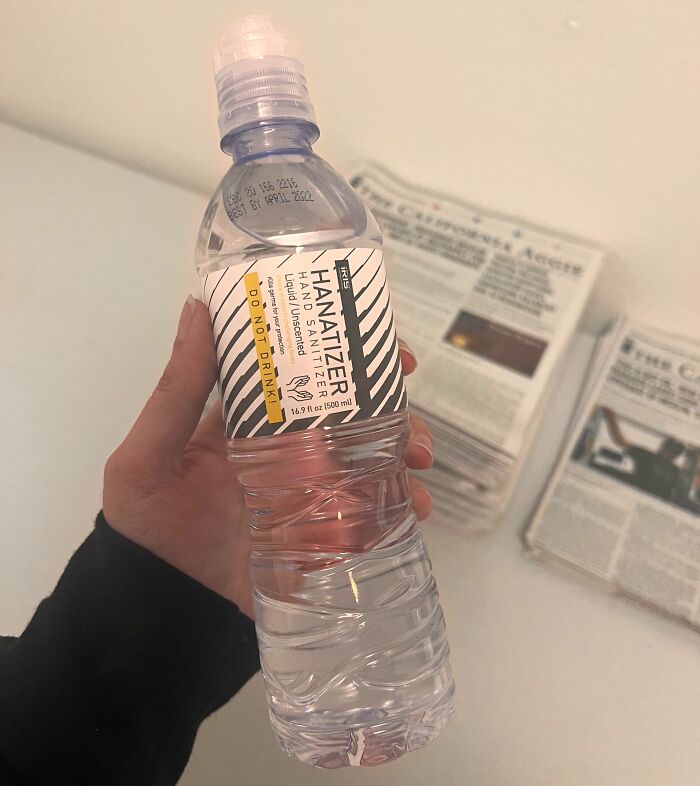 Hand holding a dangerous design hand sanitizer bottle shaped like a water bottle, a potential death trap warning.