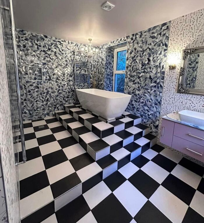 Bathroom with black and white checkered floor and steps leading to a bathtub, showcasing dangerous designs and potential death traps.