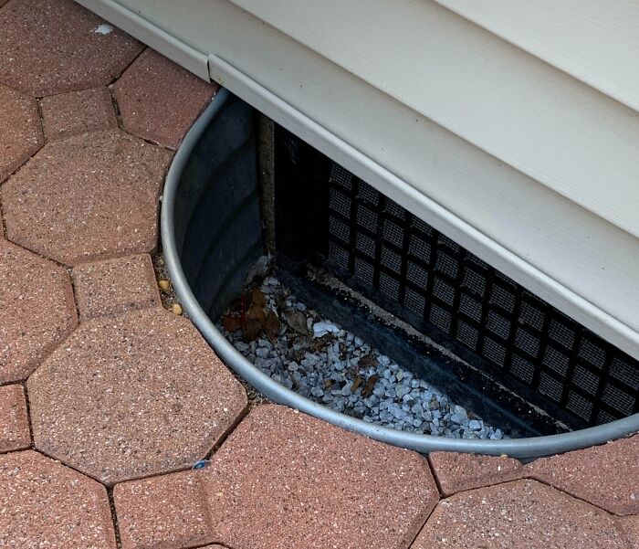 Window well with sharp edge and debris inside, illustrating one of the dangerous designs that could be classified as death traps.