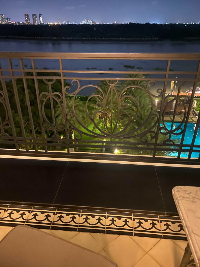 Balcony railing with dangerous design overlooking a river at night, featuring potential death trap hazards in the structure.
