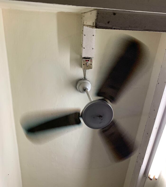 Old ceiling fan with a worn, rusty mount and exposed wiring, an example of dangerous designs and potential death traps.