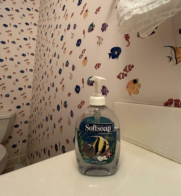 Softsoap antibacterial hand soap with fish design on counter in bathroom with fish wallpaper, a bizarre thing in old houses.