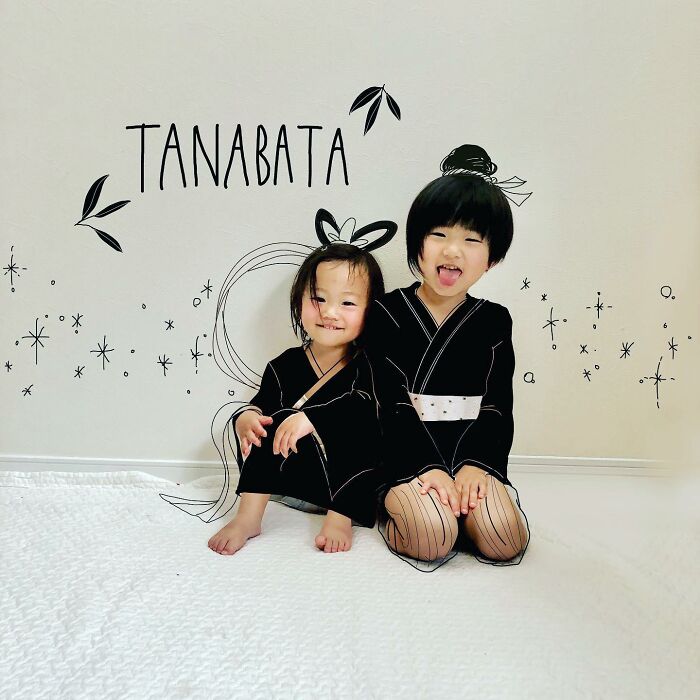 Two kids in black outfits with playful drawings added, showcasing a Japanese father's adorable artwork on photos.