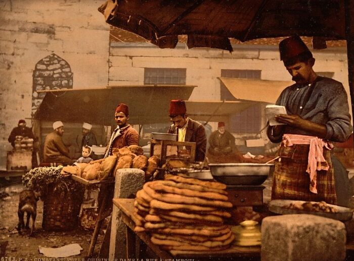 Colorized photo showing a vibrant market scene with bakers and traditional attire revealing cultural past details.