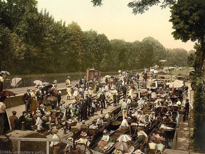Colorized photo showing a lively historic scene with people gathered along a canal, revealing vibrant cultural past.