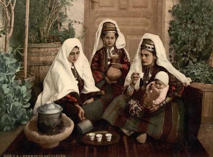Colorized photo of women in traditional dress serving tea, showcasing vibrant cultural past and historical heritage.