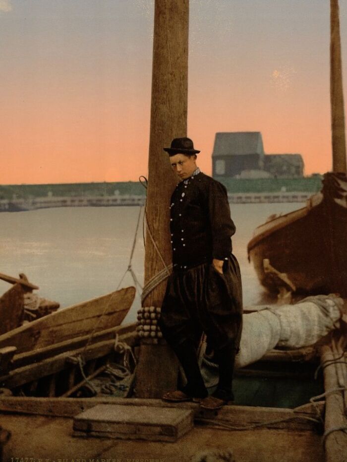 Colorized photo of a man wearing traditional clothing on a boat revealing the world's vibrant cultural past.