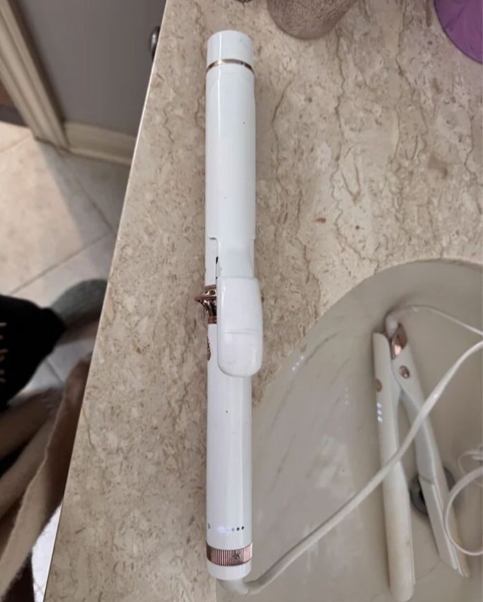 White damaged curling iron on a bathroom countertop illustrating dangerous designs and potential death traps.