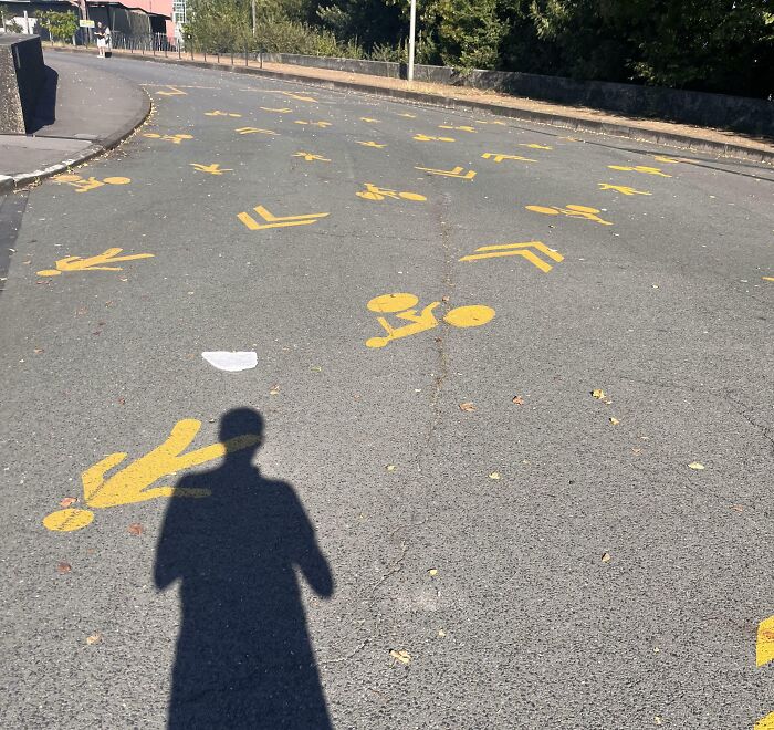 Multiple confusing yellow pedestrian and cyclist symbols scattered across a road, illustrating dangerous designs.